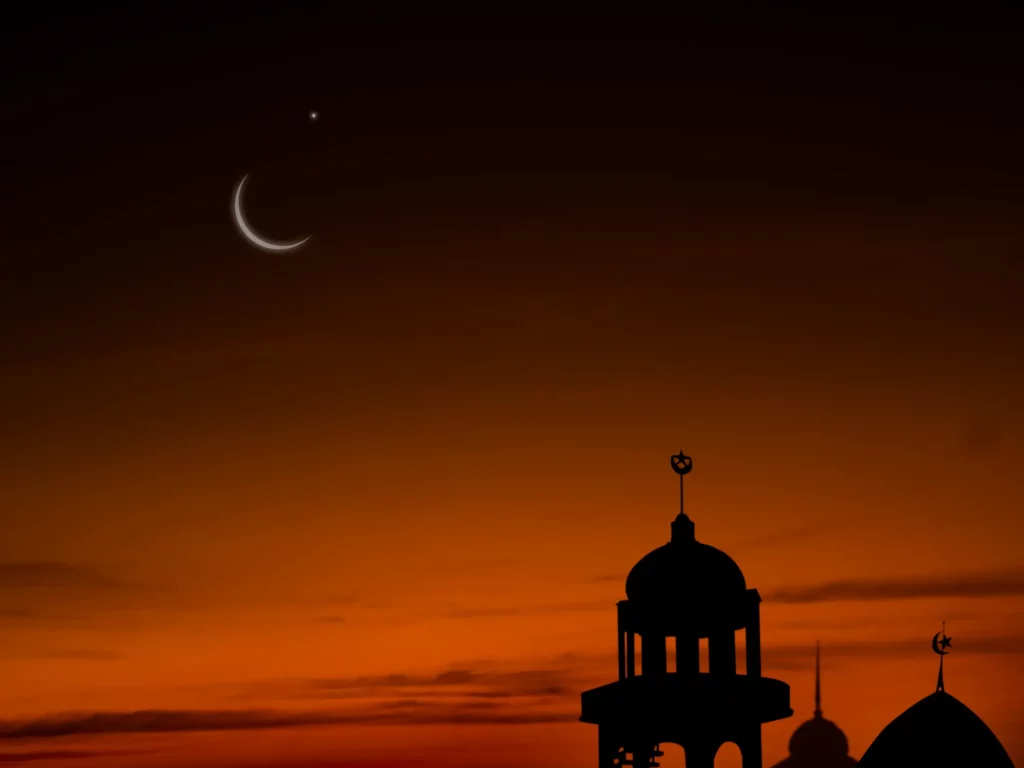 Coucher de soleil sur une mosquée avec la lune visible en arrière-plan